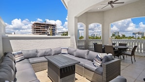A covered outdoor seating area with a sofa, chairs, and a table, overlooking a cityscape. - Birch Road Beach House | Oceanfront | Luxury Villa (Fort Lauderdale)