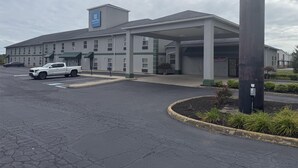 A multi-story hotel with a covered parking area, a SureStay FirstNet sign, and a building labeled 'Under New Management'. - Surestay By Best Western Obetz Rickenbacker Airport (Obetz)