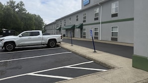 A parking lot with a white pickup truck, a building with a sign reading "SureStay by Best Western," and a handicapped parking sign. - Surestay By Best Western Obetz Rickenbacker Airport (Obetz)