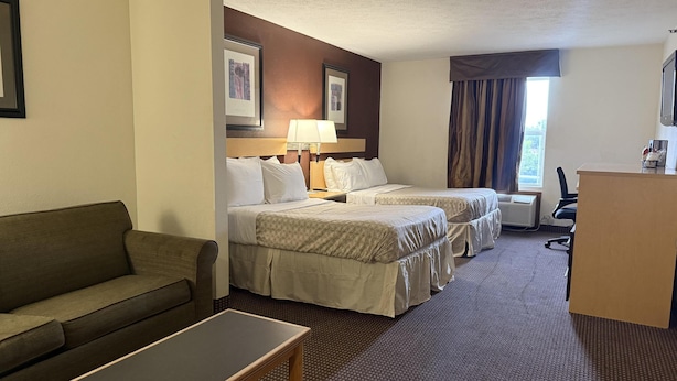 A hotel room with two beds, a sofa, a desk, and a window with curtains. - Surestay By Best Western Obetz Rickenbacker Airport (Obetz)