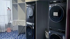 A laundry room with multiple washing machines, a drying rack, and a table with a white tablecloth.