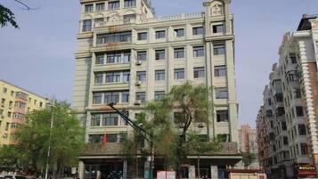 A multi-story building with a prominent entrance and a flag.