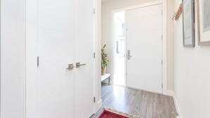 A hallway with white doors, a wooden floor, and a red rug. - Steps from Trails and Village Shops (Highlands)