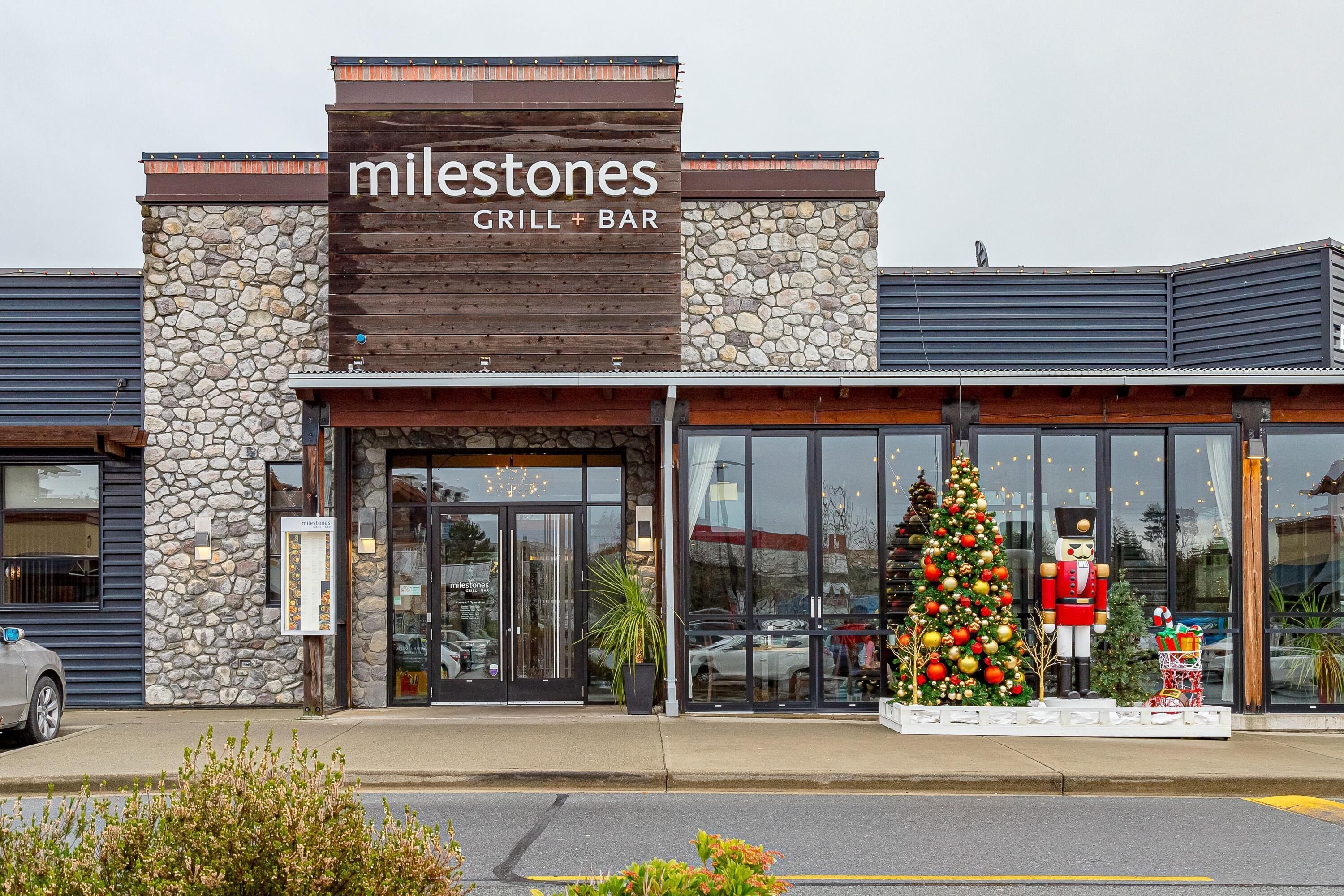 A restaurant named 'Milestones Grill & Bar' with a stone facade and a Christmas tree display outside.