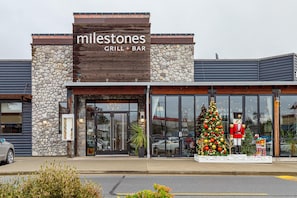 A restaurant named 'Milestones Grill & Bar' with a stone facade and a Christmas tree display outside. - Steps from Trails and Village Shops (Highlands)
