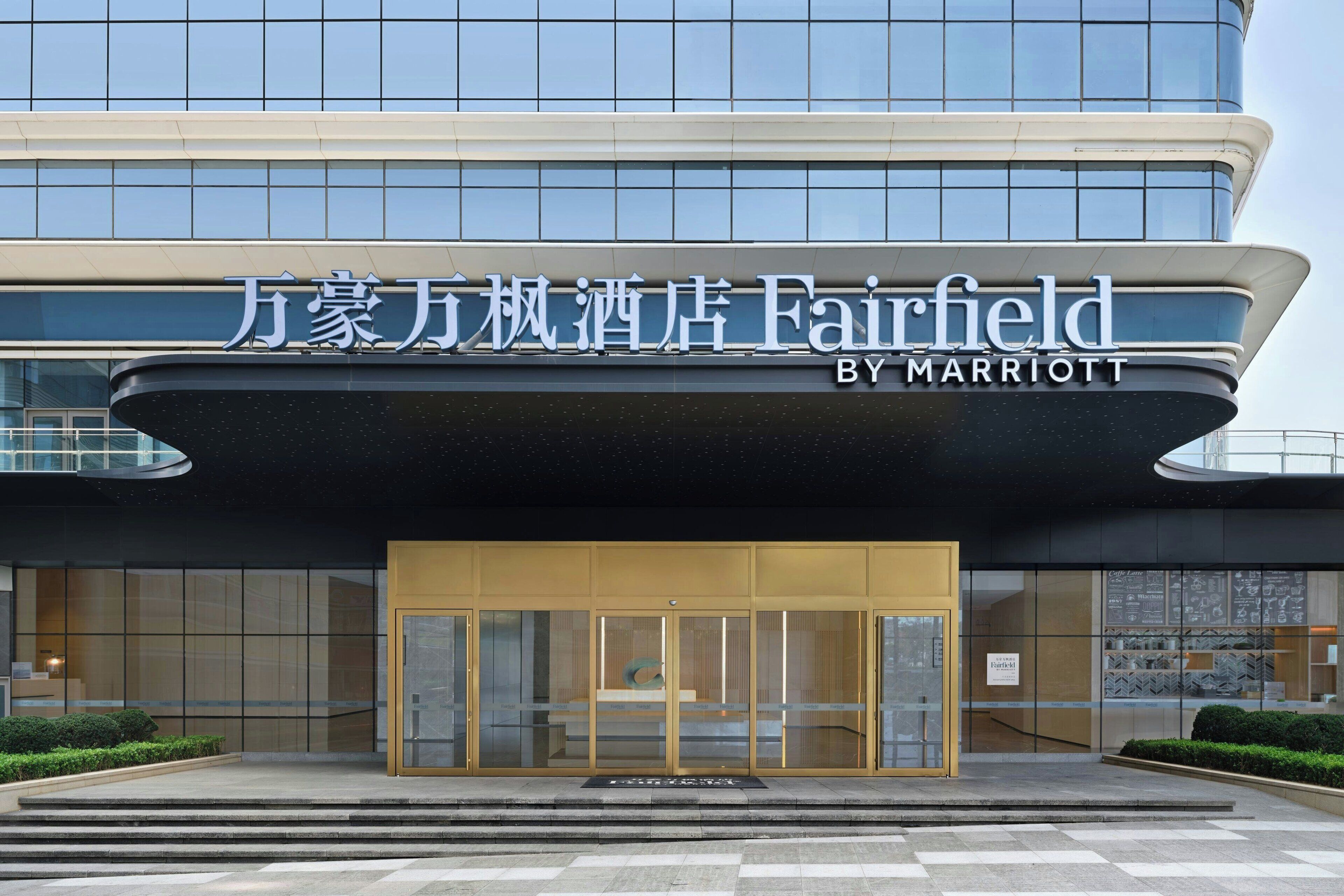 A modern hotel entrance with a glass facade and a sign indicating it is a Marriott property.
