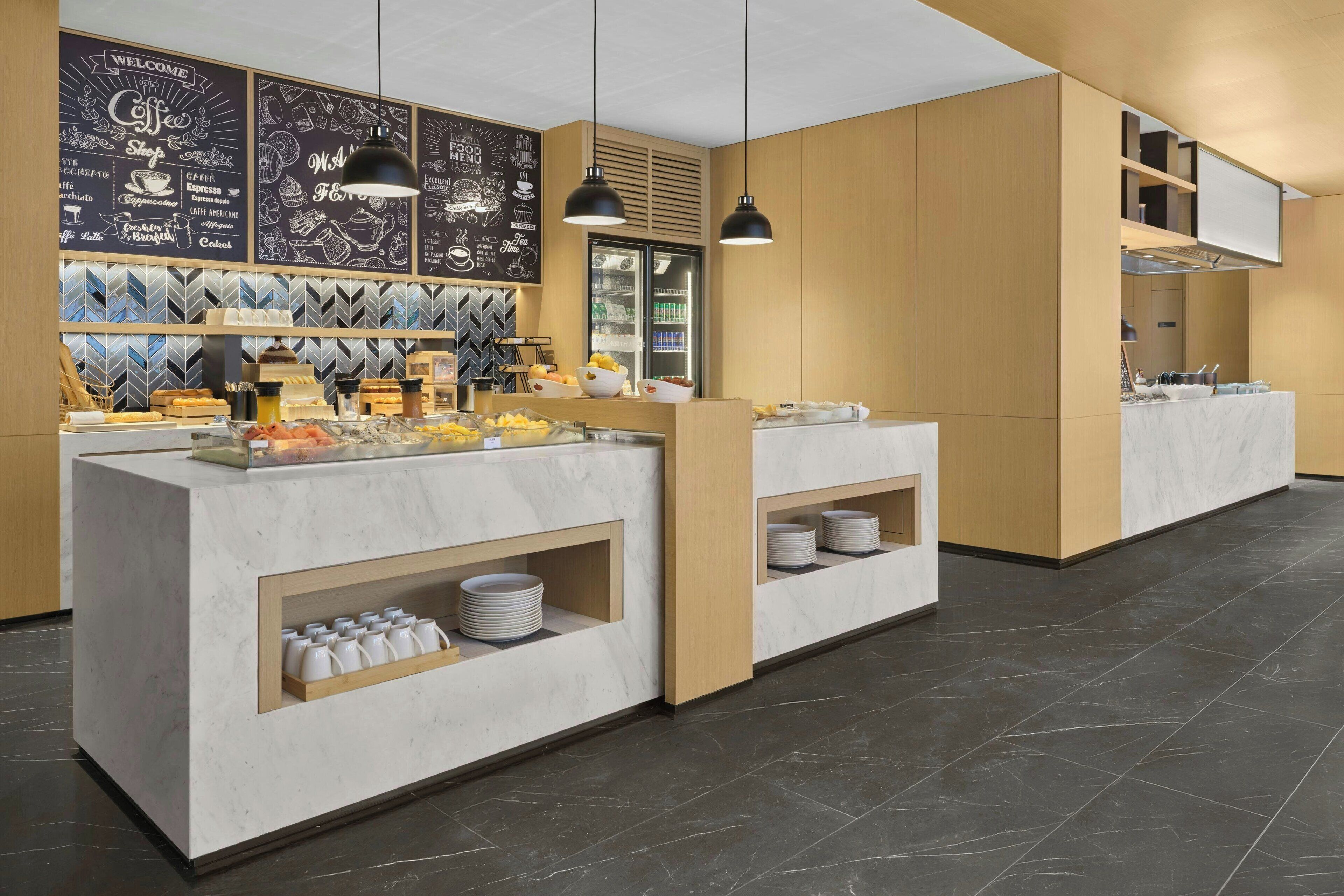 A modern coffee shop with a marble counter, black pendant lights, and a chalkboard menu.