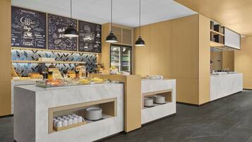 A modern coffee shop with a marble counter, black pendant lights, and a chalkboard menu.