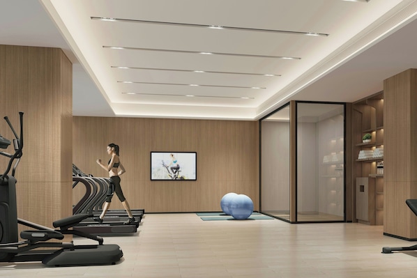 A modern gym with treadmills, a large exercise ball, and a wall-mounted TV.