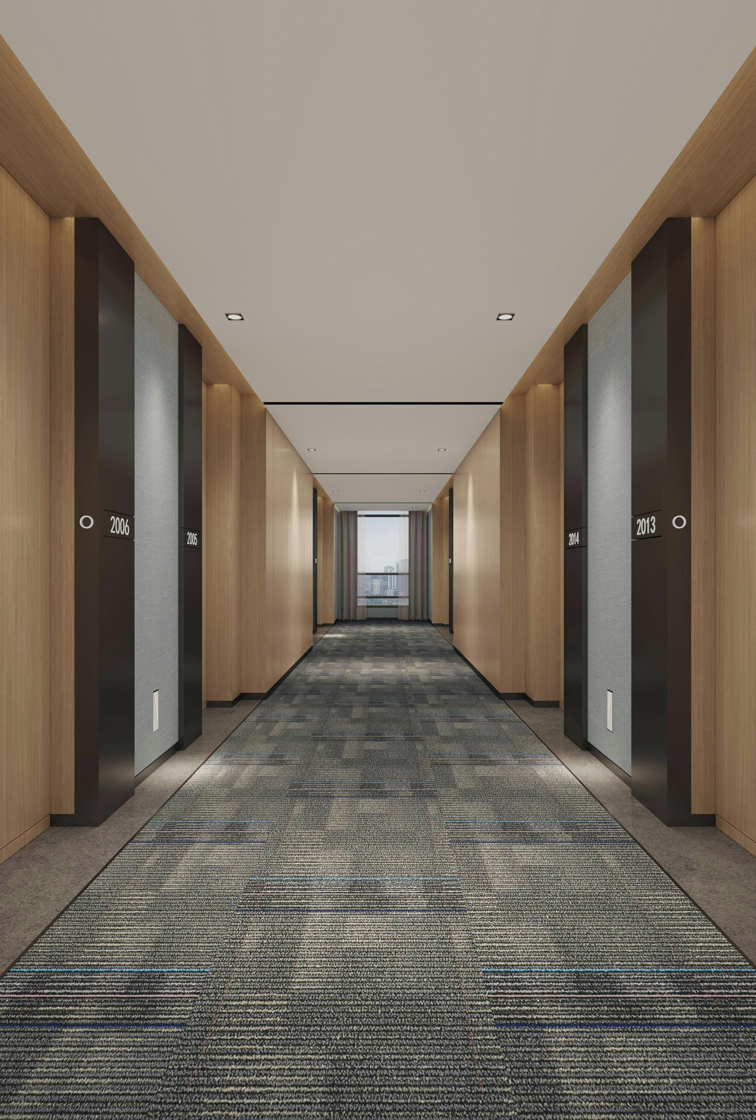 A modern hotel hallway with wooden paneling, carpeted floors, and numbered doors indicating room assignments.