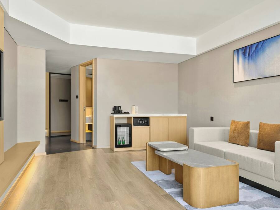 Uma sala de estar moderna com sofá, mesa de centro e cozinha planejada, incluindo geladeira e micro-ondas.