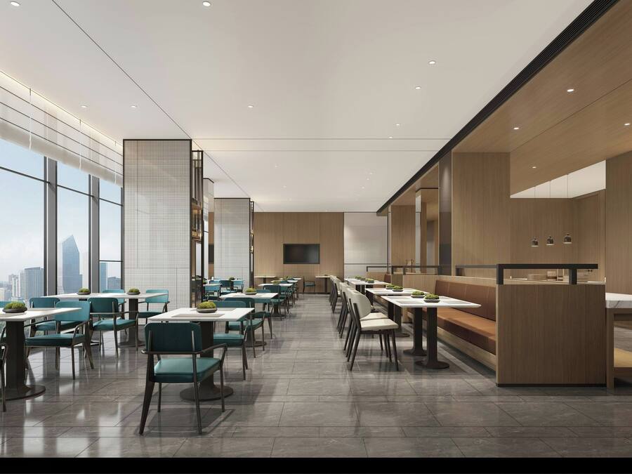Un restaurante moderno con techos altos, ventanas amplias y vista a la ciudad. Las mesas están dispuestas en un espacio amplio con sillas verdes.