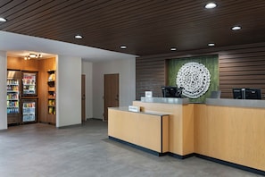 A reception area with a wooden reception desk, a refrigerator stocked with beverages, and a wall-mounted decorative item.