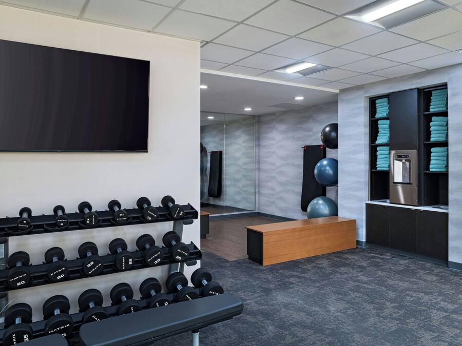 A gym with weightlifting equipment, a television, and a water dispenser.