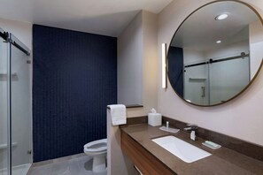 A modern bathroom with a glass shower enclosure, a toilet, a sink with a mirror, and a towel rack.