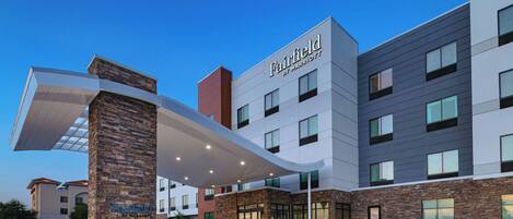 Un hotel Fairfield by Marriott con un diseño moderno, que presenta fachada de piedra, múltiples ventanas y un área de entrada cubierta.