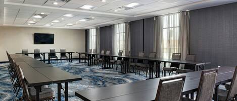 A conference room with a long table, chairs, and a large screen.