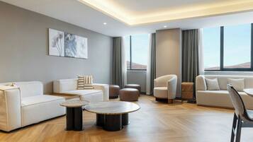 Una sala de estar moderna con un sofá, sillones, otomanas, una mesa de centro y obras de arte en la pared.