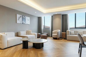 Una sala de estar moderna con un sofá, sillones, otomanas, una mesa de centro y obras de arte en la pared.