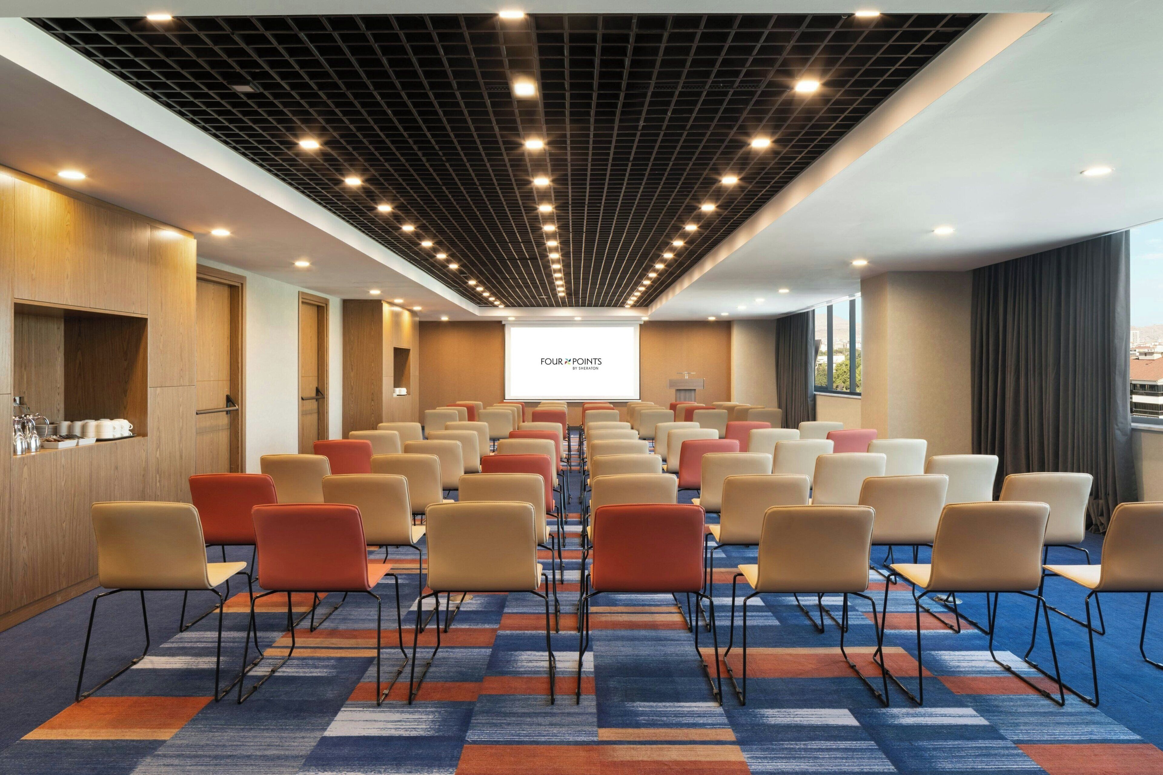 A conference room with rows of chairs, a projector screen, and a presentation titled "FOUR POINTS".