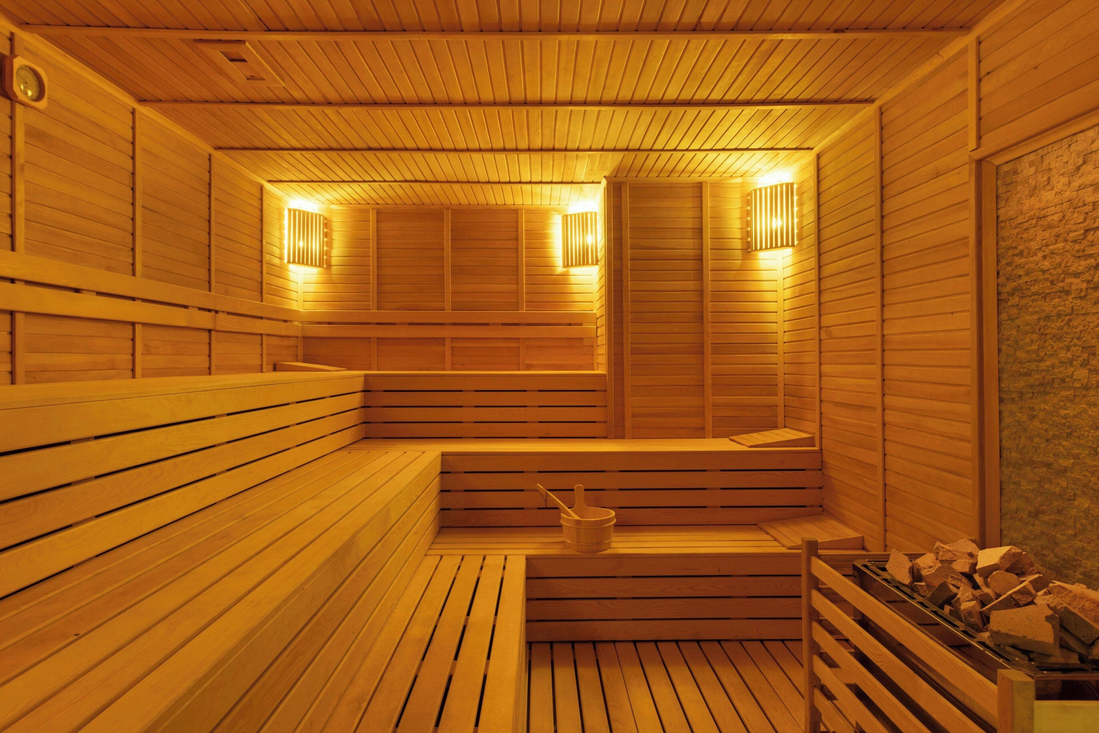 A wooden sauna with benches and a small table with a bucket.