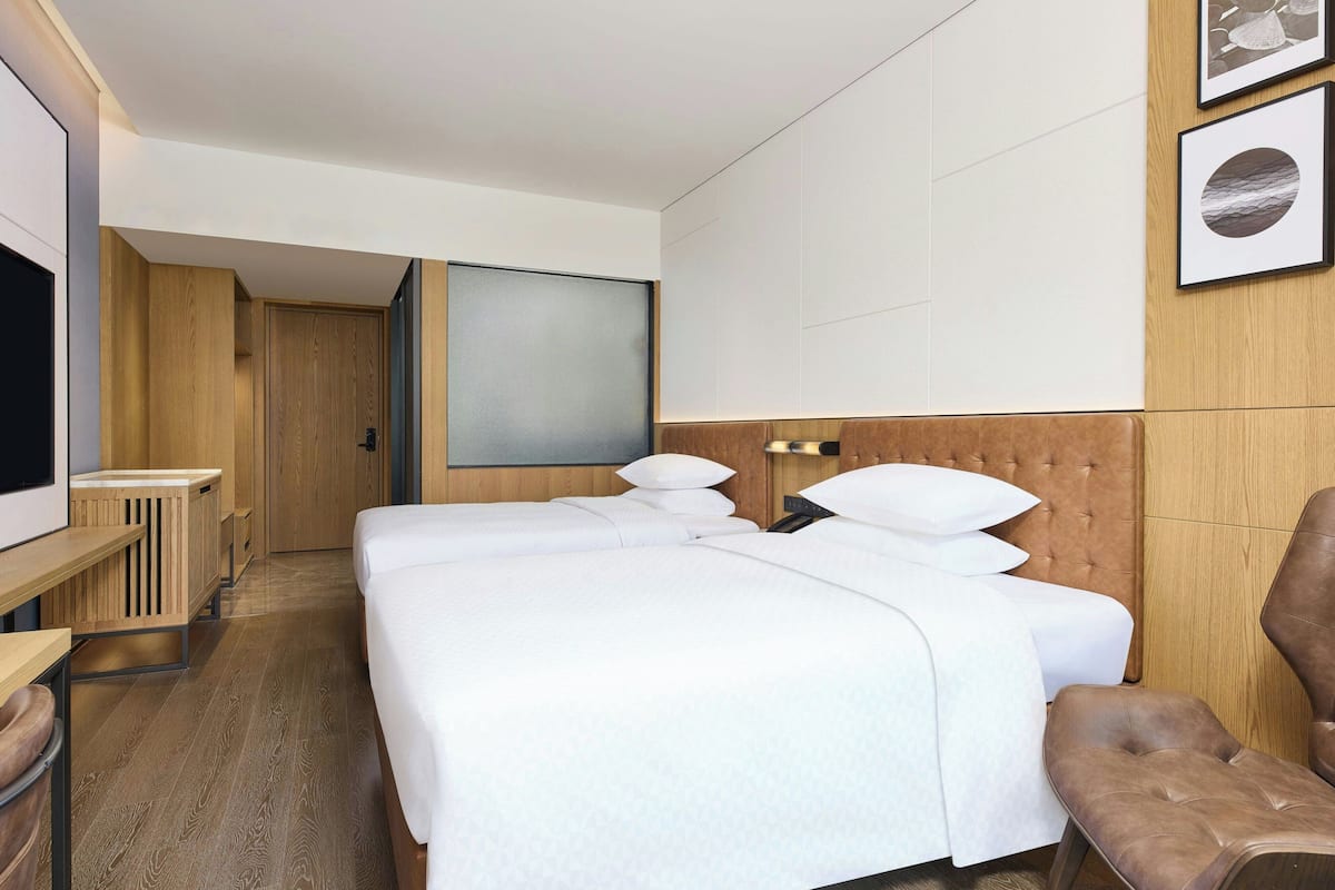 A hotel room with a large bed, a TV, a desk, and a chair.