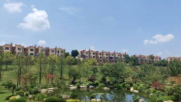 A residential complex with multiple apartment buildings, a well-maintained garden with a pond, and a stone pathway.