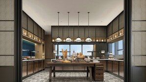 Een moderne keuken met een centraal eiland, hangende lampen en een groot raam met uitzicht op de stad.