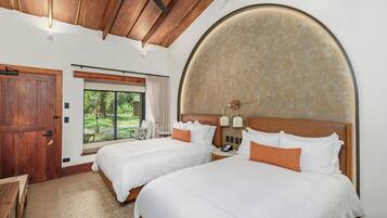 A hotel room with two beds, a wooden ceiling, a large window, and a round wall feature.