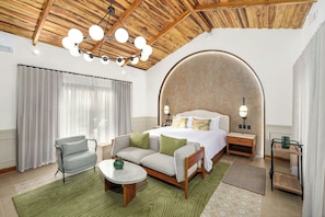 A hotel room with a bed, a sofa, a small table, a nightstand, and a ceiling fan. - Santa Lucia Jungle Hacienda, Costa Rica, Autograph Collection® (Tárcoles)