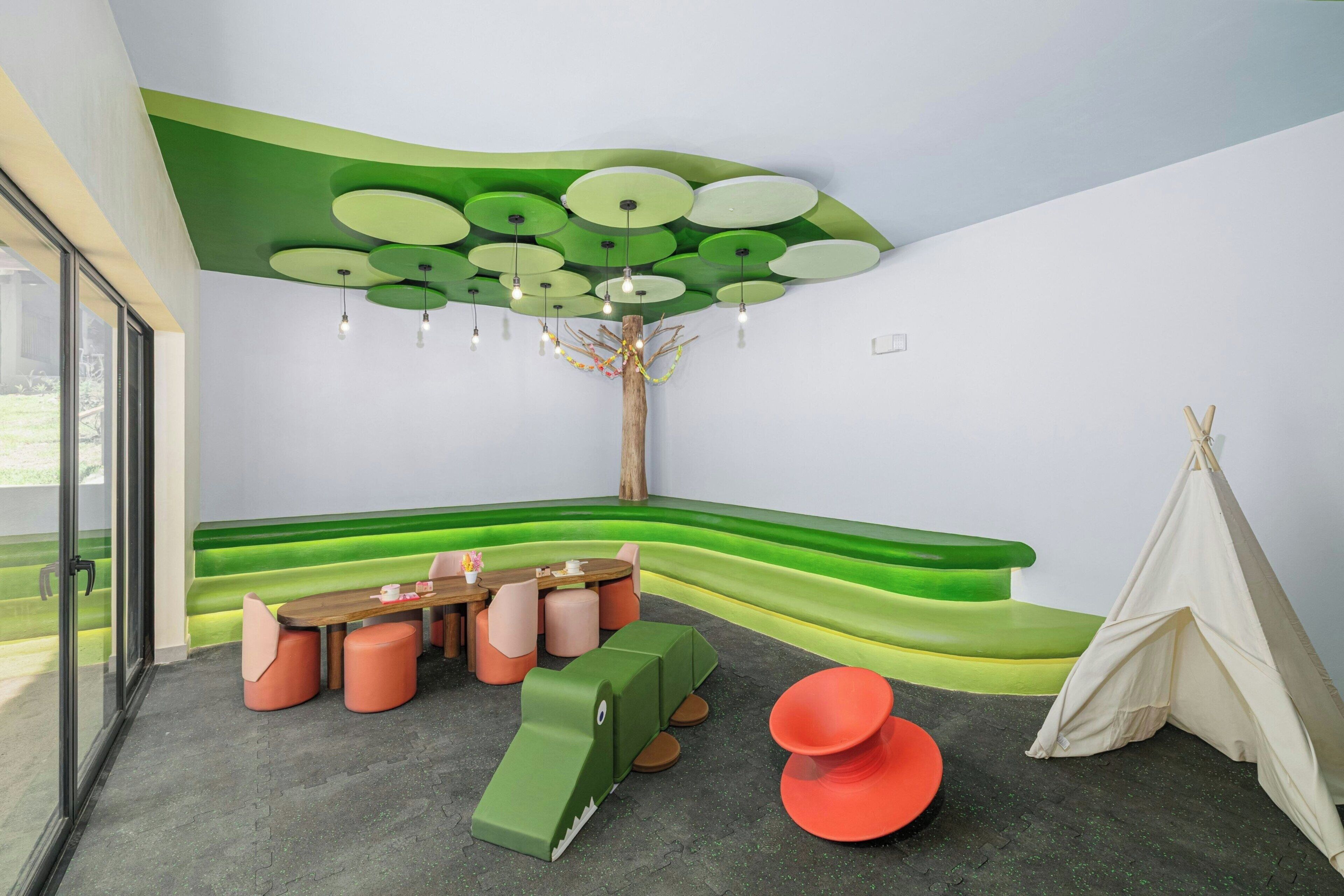 Ein modernes Interieur mit Grün-Weiß Farbgebung, einem runden Tisch mit Stühlen, einer Couch, einem roten Sessel und einer zeltartigen Konstruktion.