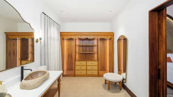 Un baño con lavamanos de piedra, tocador de madera y un espejo grande.