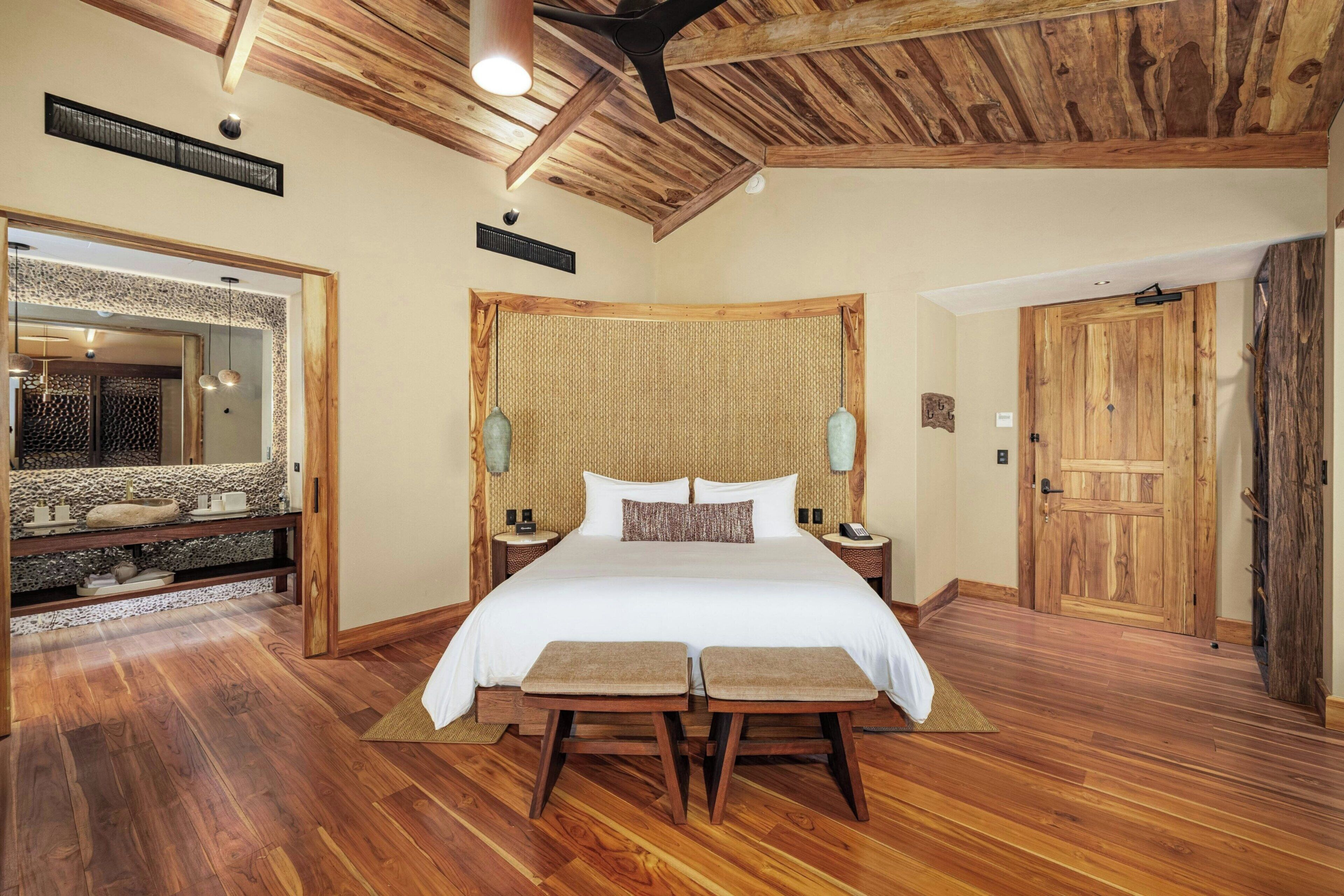 Une chambre spacieuse avec un grand lit, un plancher en bois et un ventilateur de plafond.