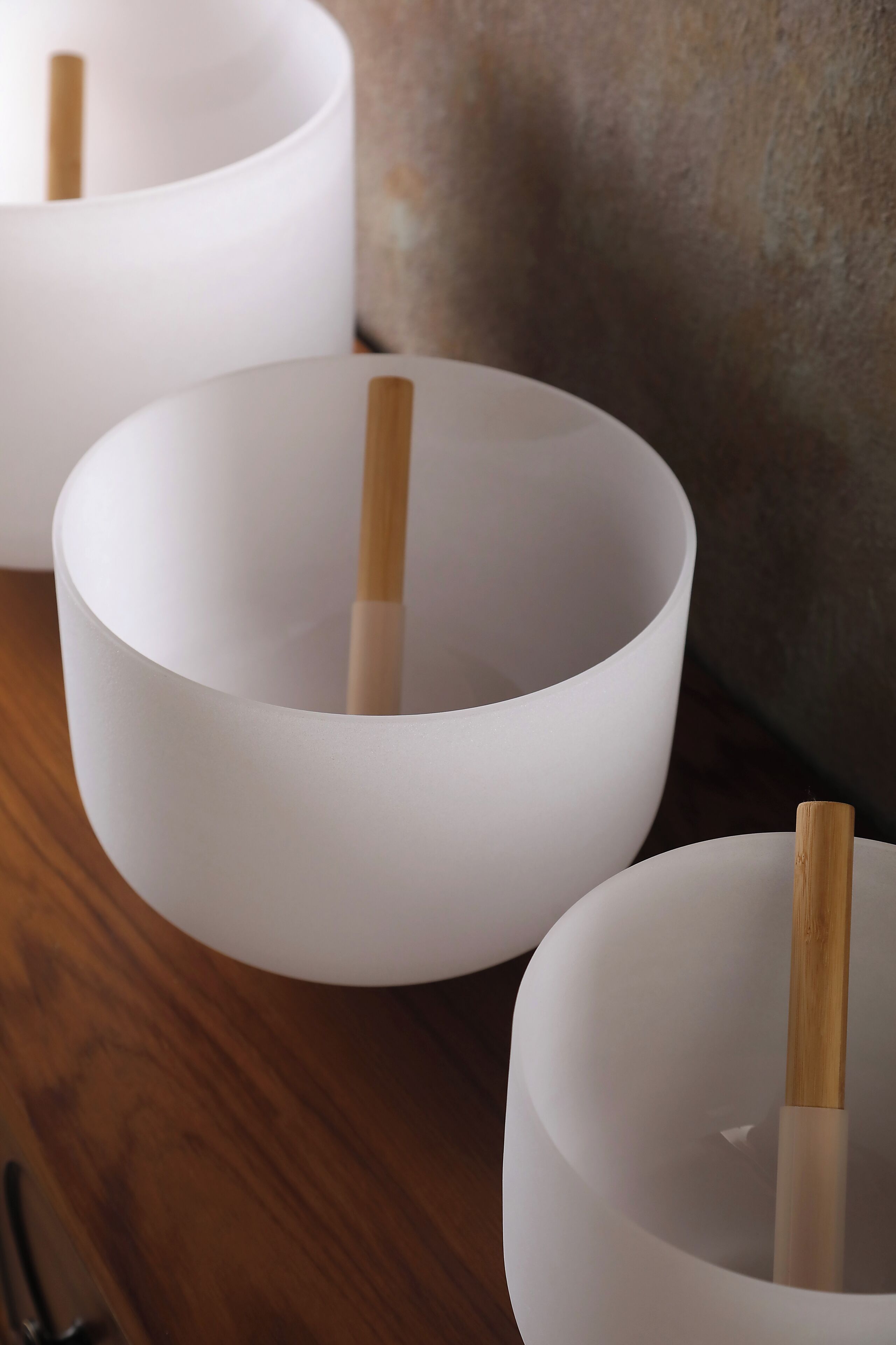 Three white bowls with wooden sticks, placed on a wooden surface.