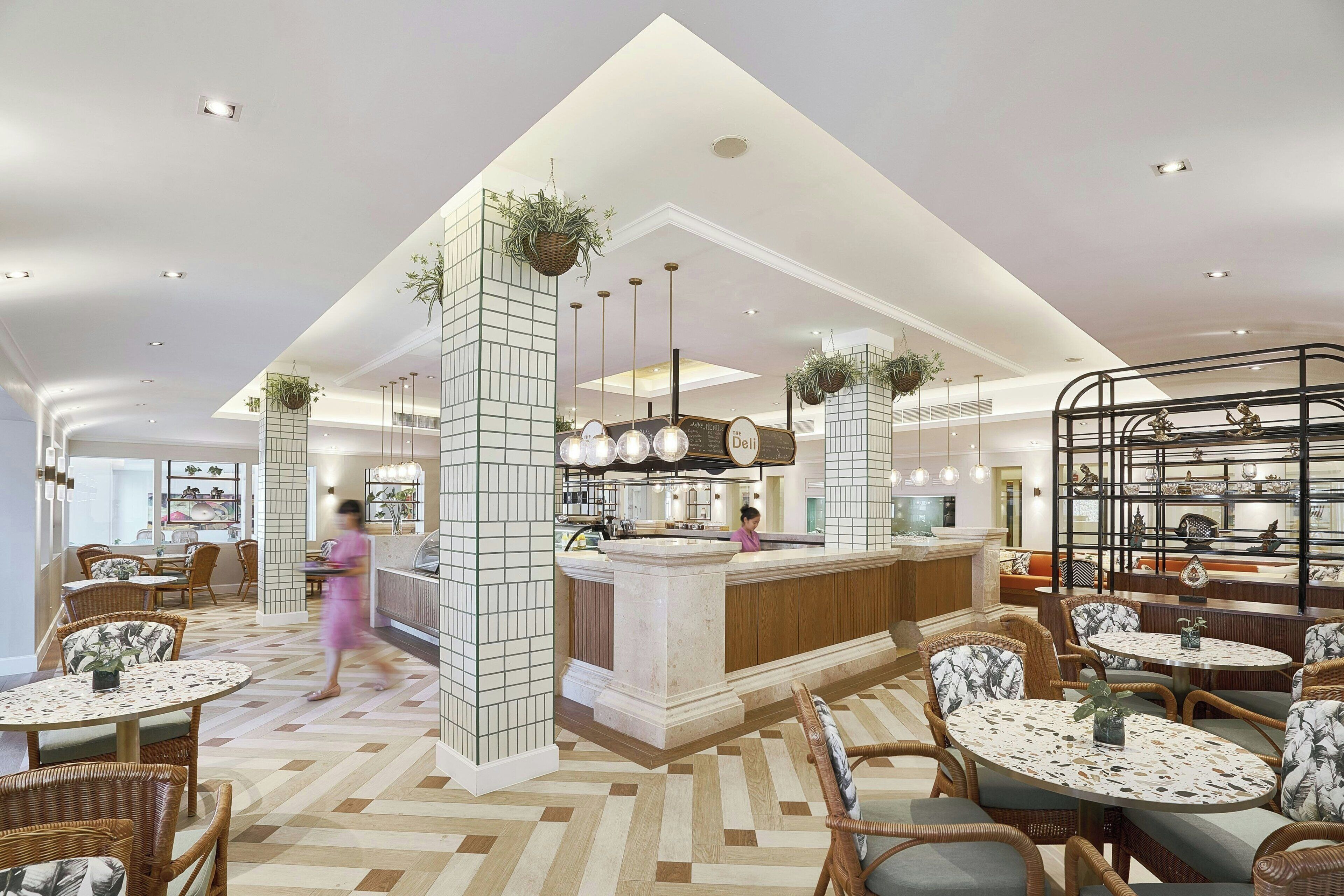 A spacious hotel lobby with a central bar area, seating arrangements, and decorative plants.