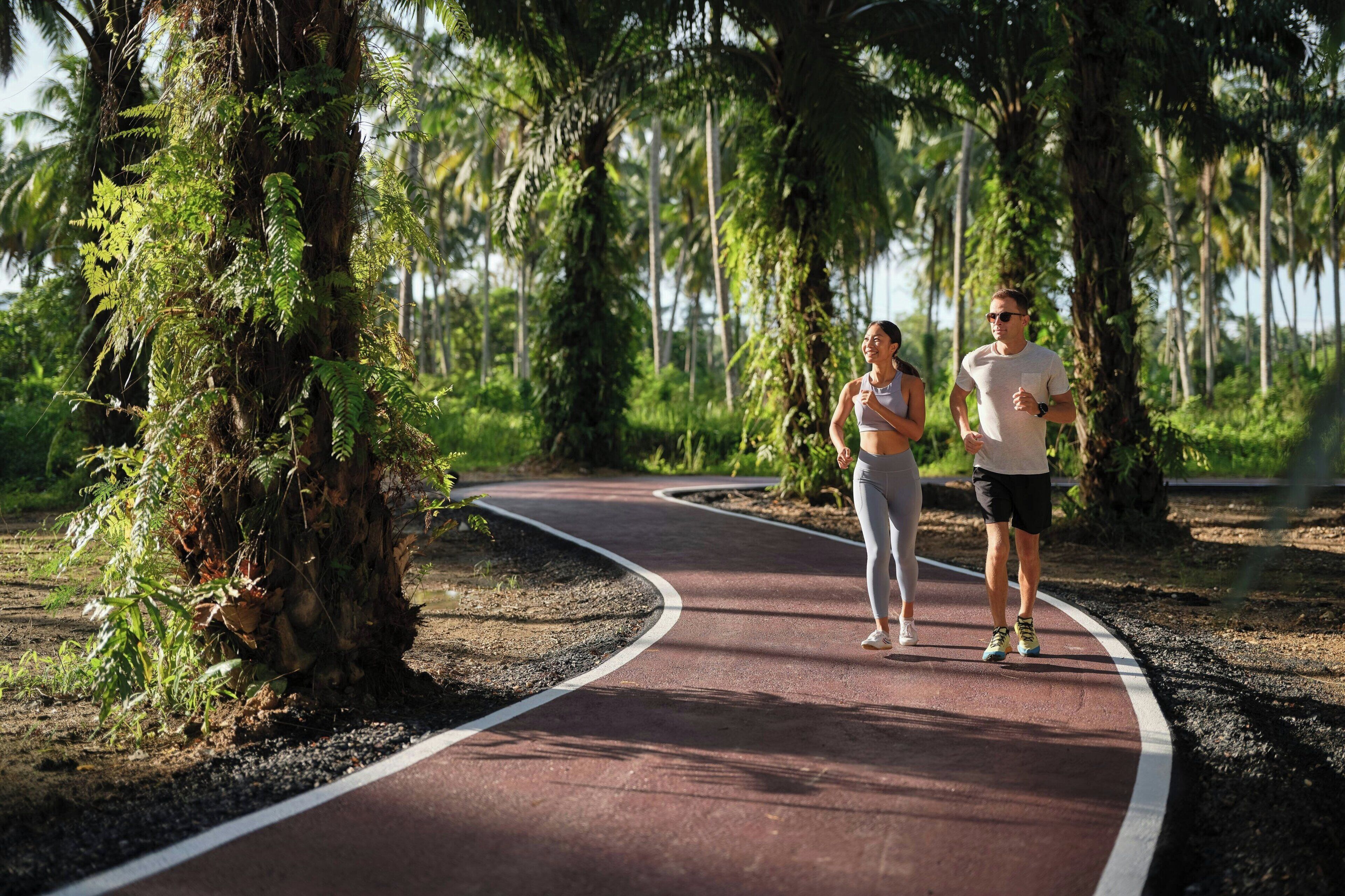 A paved jogging path with greenery and trees on both sides.