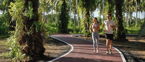 A paved jogging path with greenery and trees on both sides.