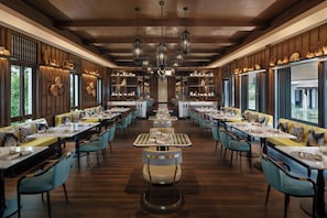 A spacious restaurant with high wooden ceilings, multiple hanging light fixtures, and a central seating area with round tables and chairs. - Marriott Vacation Club, Khao Lak Beach Resort (Takua Pa)