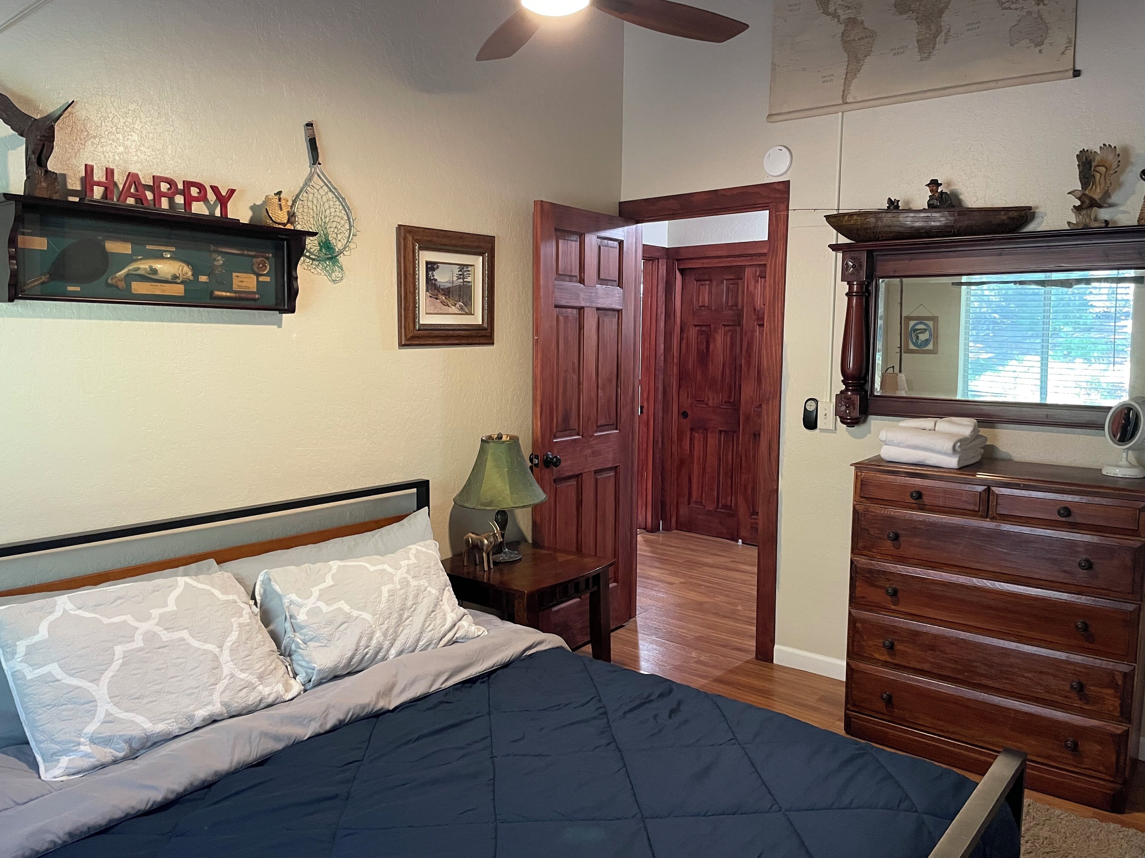 A bedroom with a bed, dresser, and a wooden door leading to another room.