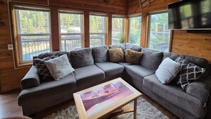 A cozy cabin interior with a large gray sectional sofa, a wooden coffee table, and a TV mounted on the wall. - CLOSEST HOME TO A CHAIRLIFT & HIKING ON THE PLANET! SLEEPS 8, CLEAN, WIFI, VIEWS (Stateline)