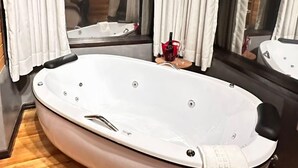 Uma banheira de hidromassagem grande e oval numa cabana de madeira com cortinas brancas e vista para uma pessoa do lado de fora.