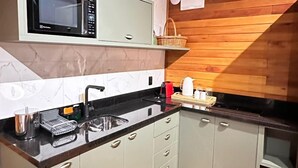 Uma cozinha compacta com micro-ondas, pia e piso de madeira.