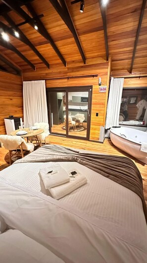 Une chambre d’hôtel comprenant un lit, une table à manger avec des chaises, un petit coin cuisine et une porte-fenêtre coulissante donnant sur un patio extérieur.