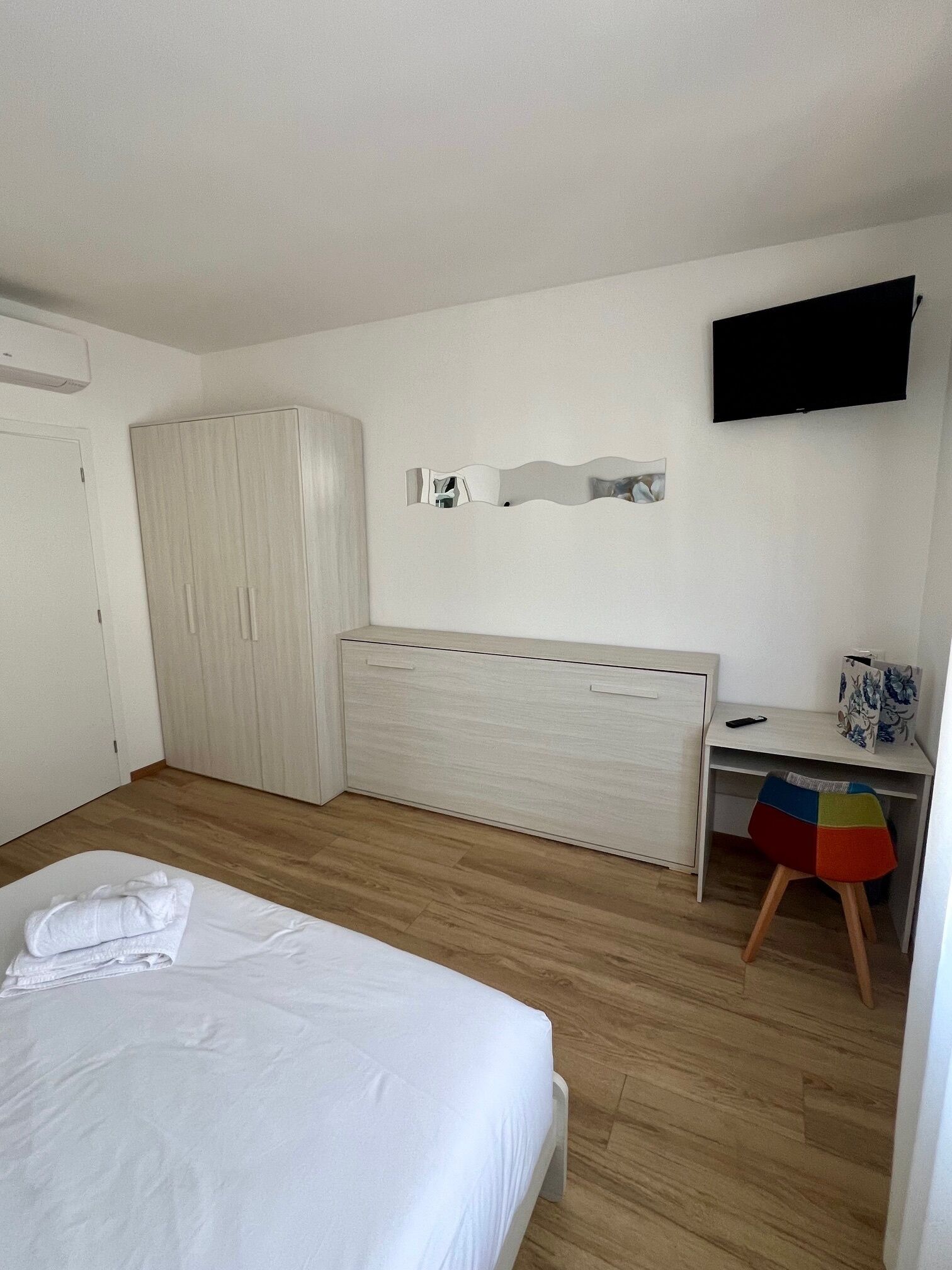 Een slaapkamer met een bed, een kledingkast, een bureau en een televisie.