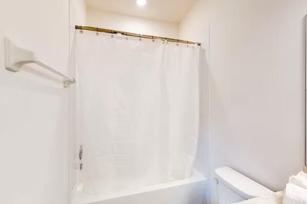 Un baño con cortina de ducha, toallero y váter.