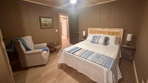 A bedroom with a bed, a chair, a nightstand, and a ceiling fan. - The Sandtown 3 bedroom Cabin (Vian)