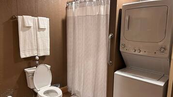 Ein Badezimmer mit Toilette, Duschvorhang und einer Waschmaschine mit Frontlader.