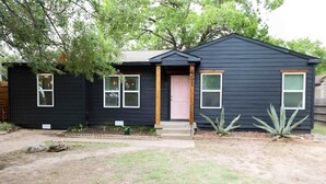 Una casa pequeña de un solo piso con fachada oscura, puerta principal y buzón.
