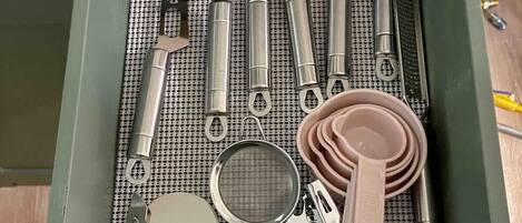 A drawer with various kitchen utensils and tools, including spatulas, tongs, and a strainer.
