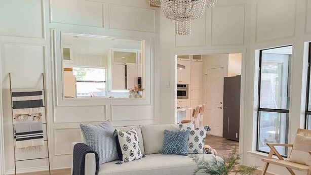 A modern living room with a white sofa, patterned cushions, a coffee table, and a chandelier. - Luxe 4BR with Heated Pool and Hot Tub - Walk to Lake (Grapevine)